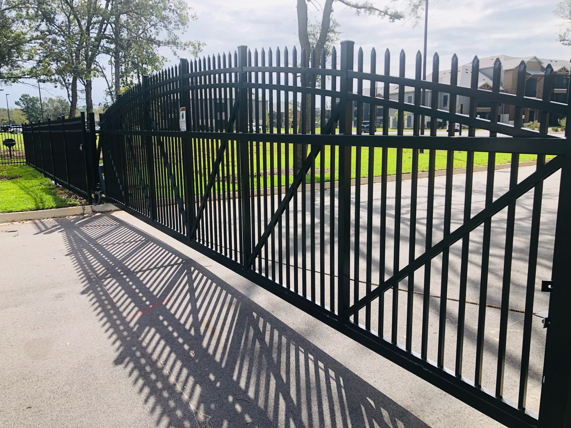 Black ornamental aluminum slide gate at a residential entrance